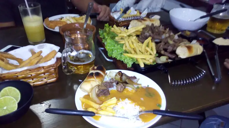 Mesa com porções, batata frita e cerveja gelada